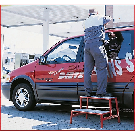 Mann auf roter Trittleiter, repariert rotes Auto. Auf dem Auto steht: "Diez Autohaus Trans Sport".